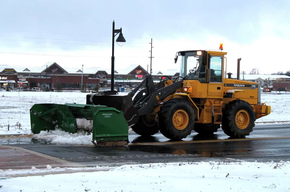 Snow plow clearing a commercial parking lot in West Virginia during winter storm